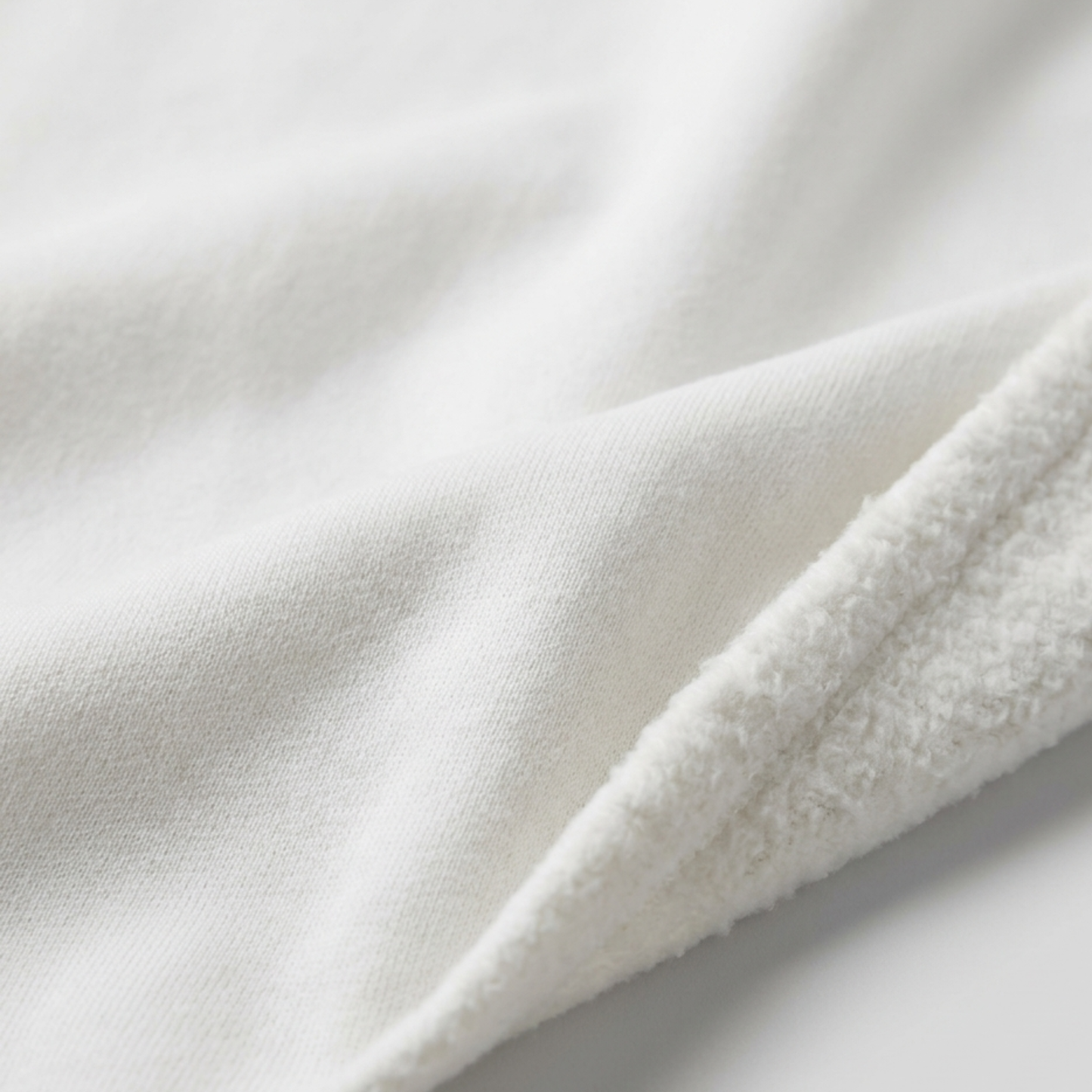 A close-up of Everglow: Silent Growth fleece hoodie fabric reveals a smooth side and a fluffy, textured side, highlighting its warmth and comfort.