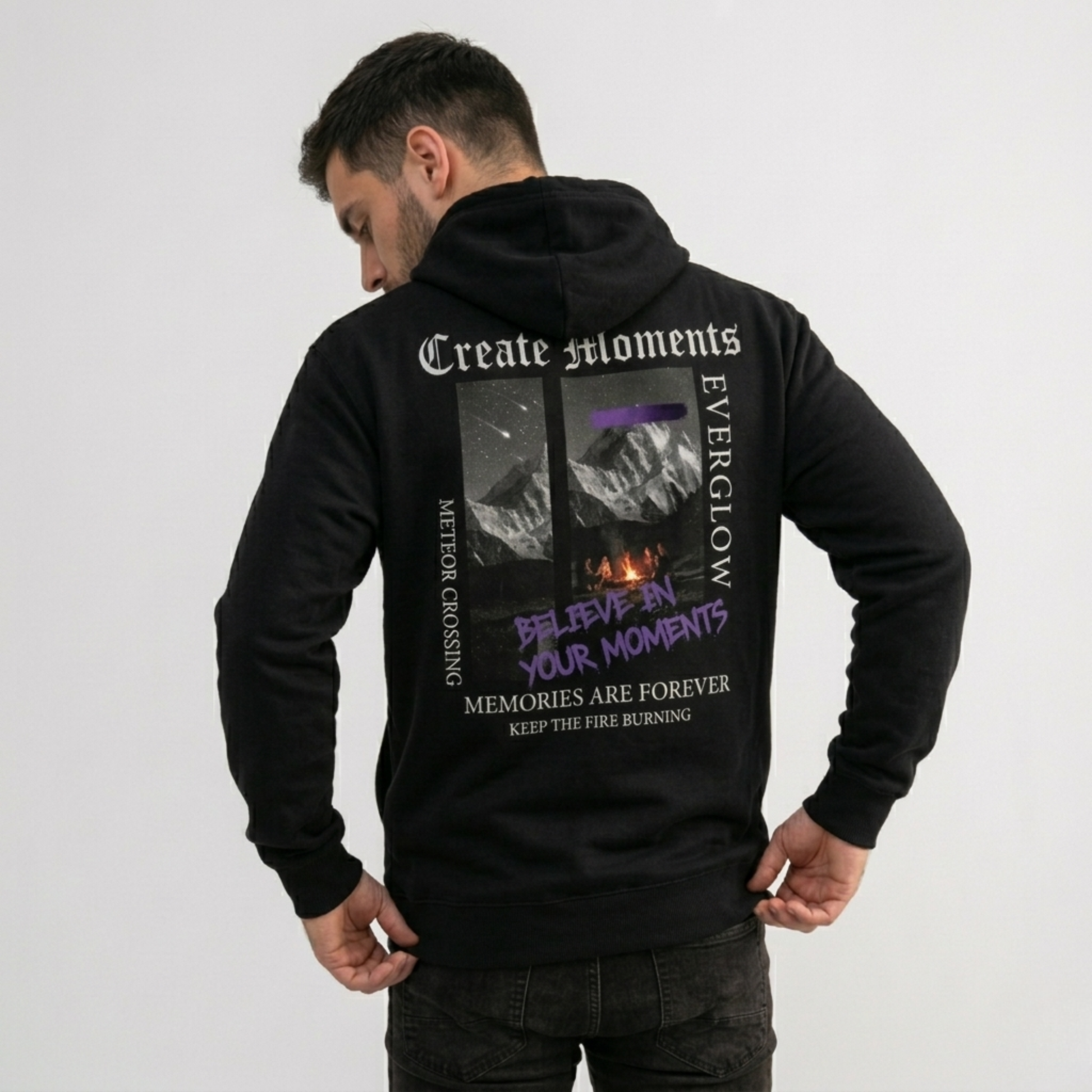 A man stands with his back to the camera in a cozy Create Memories Hoodie, featuring a mountain graphic and inspiring text like "Create Moments," "Everglow," and "Believe in Your Moments" on the back, against a plain white background.