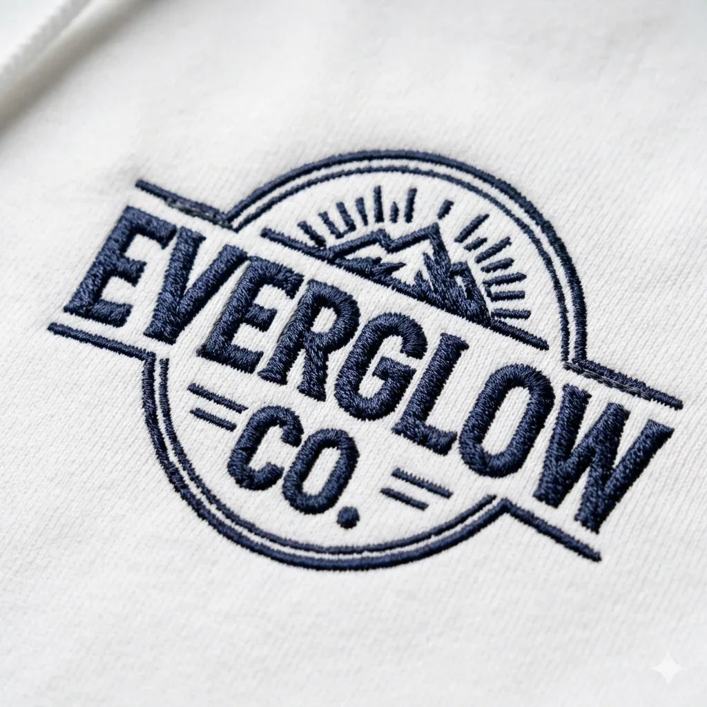 White fabric with navy embroidered EVERGLOW CO. mountain logo, nature streetwear design